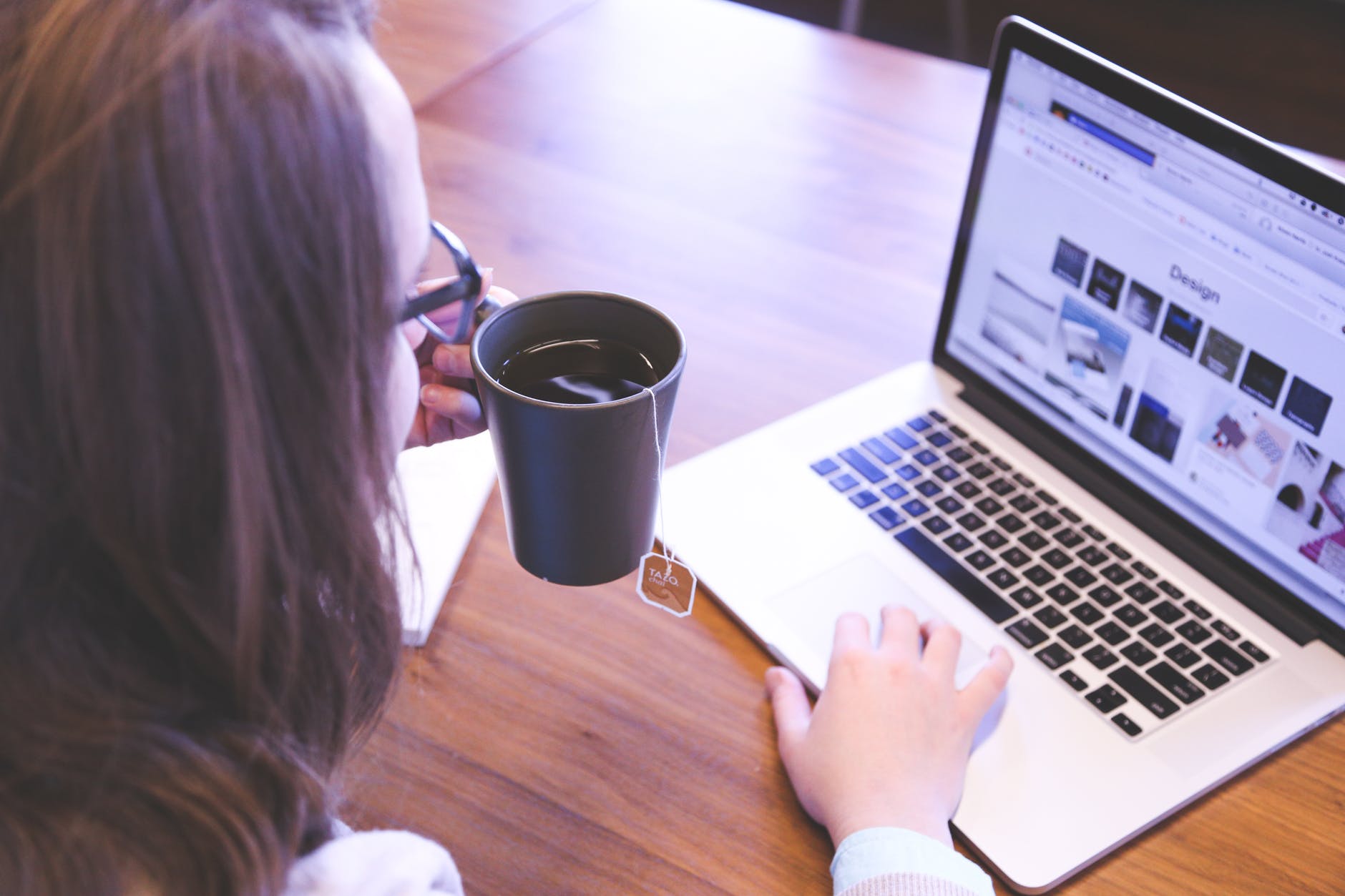 at home employee sipping from a tea cup at her laptop